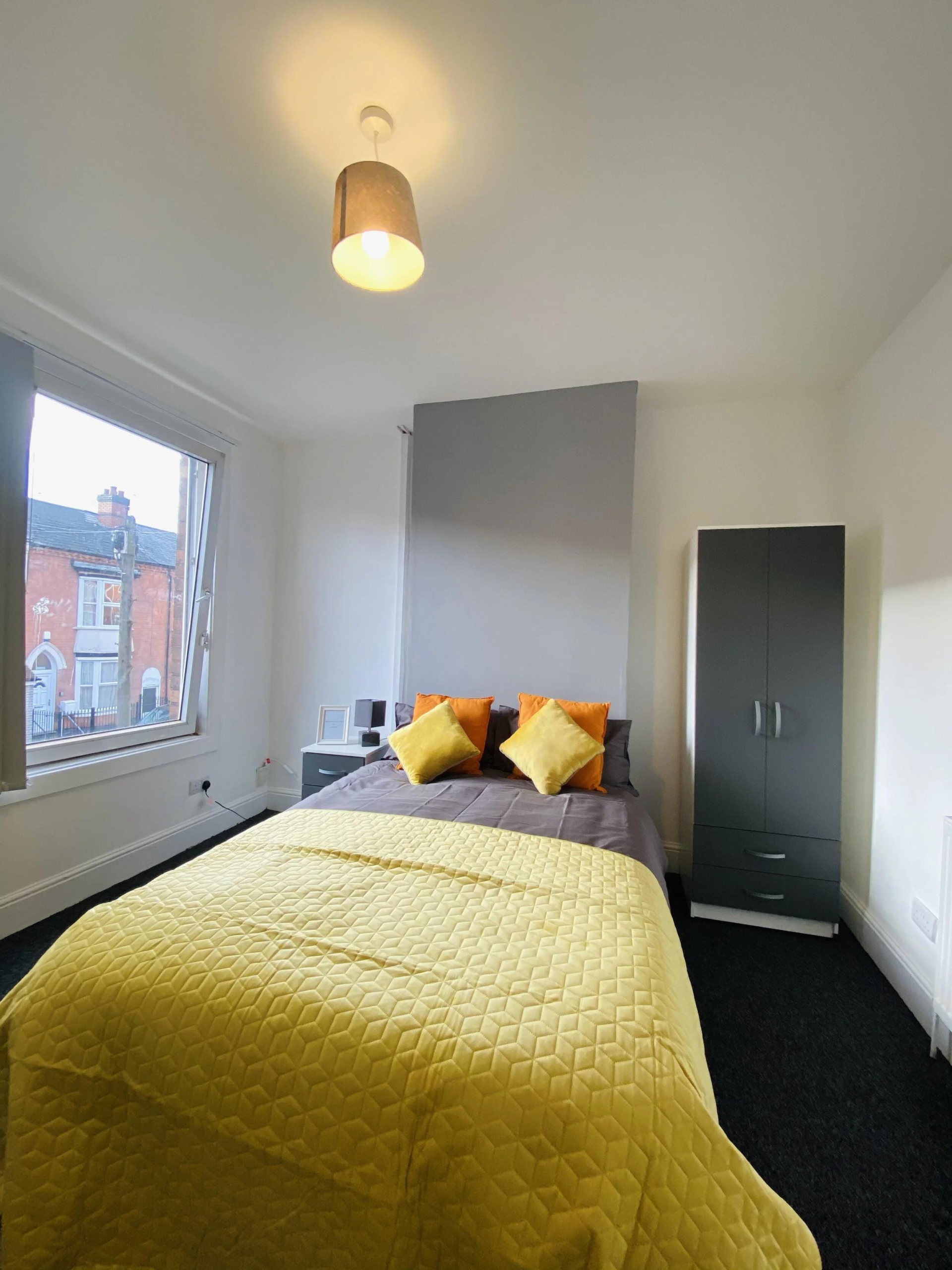 Bedroom with gray walls, yellow bedspread, and gray wardrobe near a large window