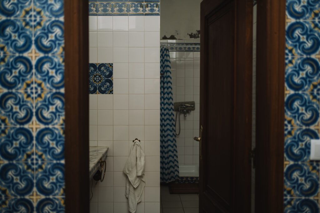 Ornate blue and yellow tiles frame a view into a tiled bathroom with a shower curtain.