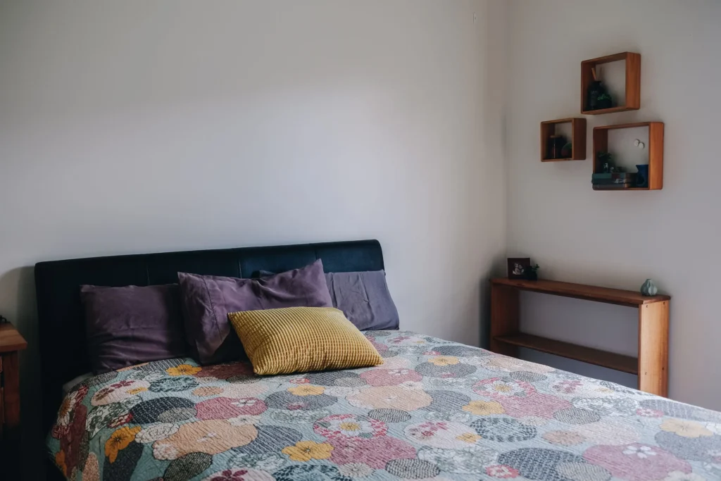 Comfortable bed with floral quilt and decorative pillows in bedroom